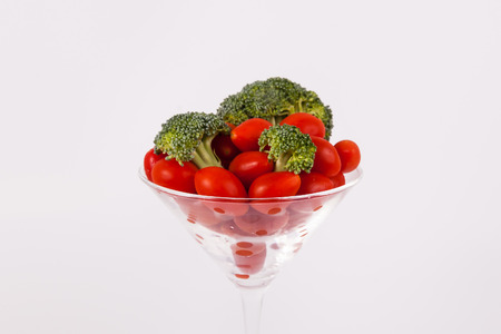 Close up cherry tomatoes and broccoli florets in martini glassの写真素材