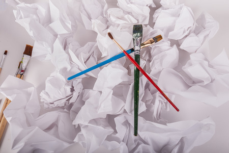 Paint brushes on top of crumbled up office copy paperの写真素材