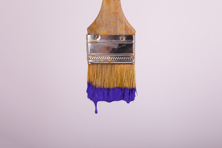 Wet purple paint dripping from 2 inch painters brush white backgroundの写真素材