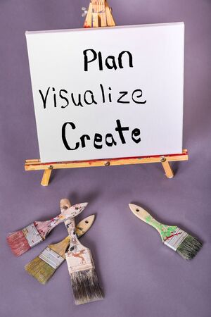 Painted words Plan Visualize Create painted on white canvas with black paint scattered paintbrushesの写真素材