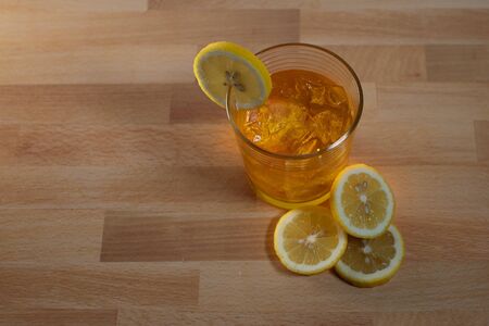 Iced beverage in rocks glass with lemon sliced on butchers wood tableの写真素材