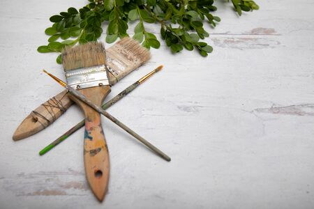 Used old dry paintbrushes laying on wooden table greenery in the backgroundの写真素材