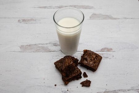 Full glass of dairy milk with chocolate brownie squares on wooden tableの写真素材