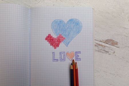 Blue heart red hart and the word love drawn on graph paper in coloring pencilsの写真素材