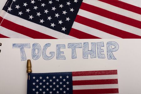 The word together hand-drawn on white paper with two American flags