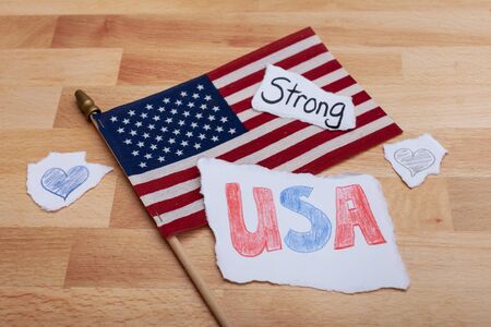 one American flag with pieces of torn paper with USA strong and hearts drawn on paper