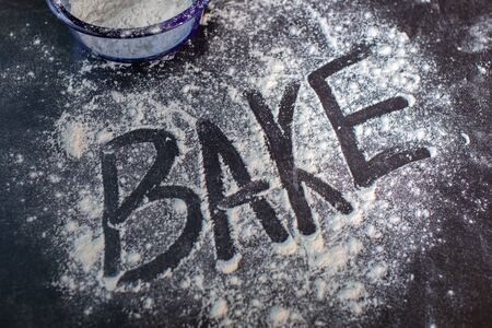The word bake written with finger on table surface in dusted spilled flourの写真素材