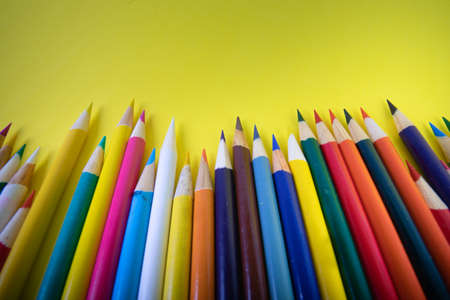 Close up of sharped colorful art coloring pencils on a bright yellow background textured backgroundの写真素材