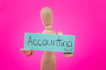 wooden manikin jointed figure holding a sign with accounting hand written on blue posterの写真素材