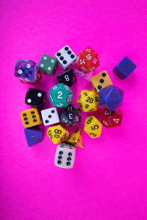 flat lay overview of assorted game dice different colors on a bright pink backgroundの写真素材