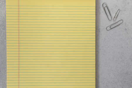 Close up yellow college ruled lined paper note pad and silver paper clips background textureの写真素材