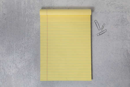 Blank empty yellow legal notepad flat lay background with office paper clips and dead spaceの写真素材