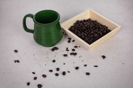 Green coffee cup square bowl filled with whole dark roasted and coffee beans dead spaceの写真素材