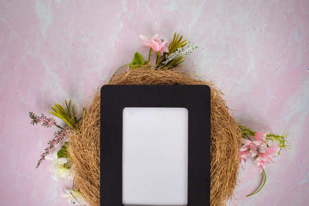 Blank frame white sign without words ready to add content flat lay background laying on bird nest with pink and white spring flowersの写真素材