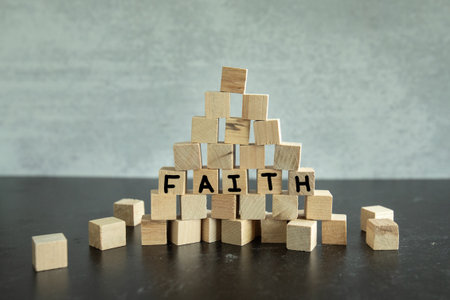 Wooden building blocks stacked in the shape of a pyramid with the word faith handwritten