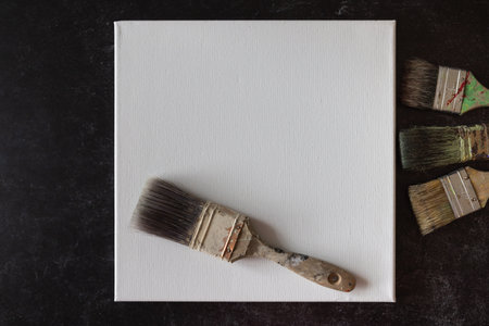 Blank empty square white canvas with one single paint brush flat lay.