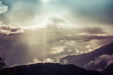 Sun rays protruting through clouds in the mountainsの写真素材