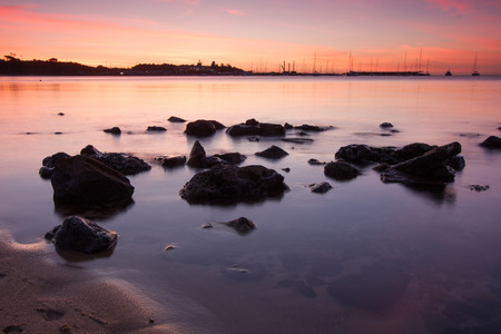 Sunset over boats with rocks in foreground.の写真素材