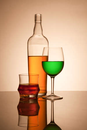 Still life composition with glasses and bottle filled with colored liquidsの写真素材