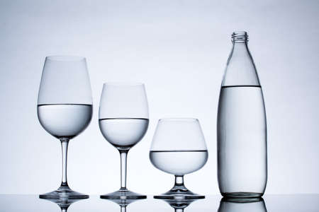 Glassware and bottle filled with water on white background.の写真素材