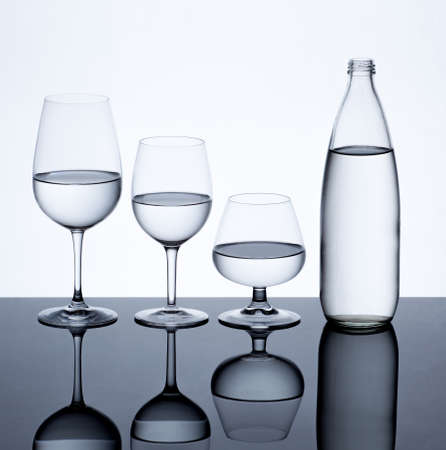 Glassware and bottle filled with water on white background.の写真素材