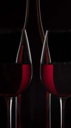 Red wine bottle and two wine glasses on black backgroundの写真素材