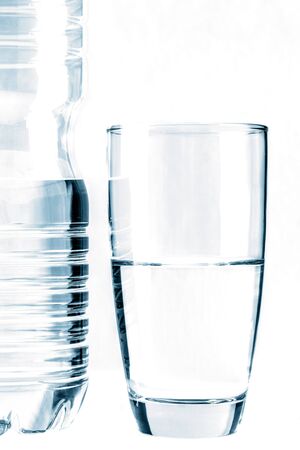 Glass of water in front of water bottle isolated on whiteの写真素材
