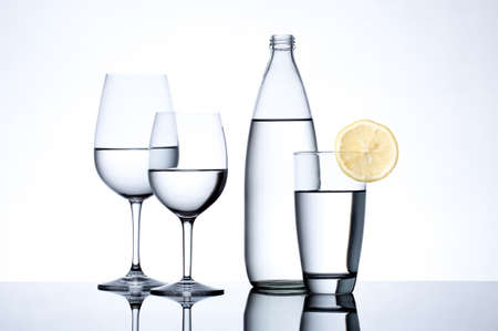 Glassware and bottle filled with water on white background.の写真素材