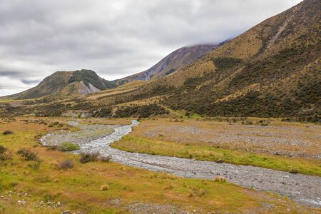 Magnificent views of yellow hills and winding river from the Great Alpine Highway, Canterbury, New Zealandの写真素材