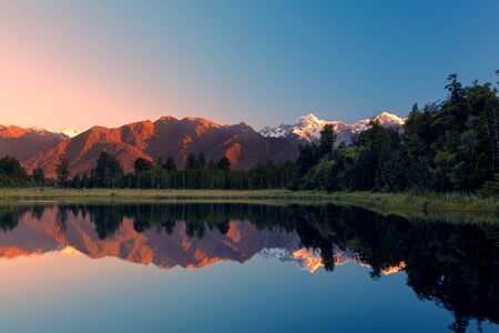 Twin Peaks reflect in the beautiful Lake Matheson at sunset, Southern Alps, South Island, New Zealandの写真素材