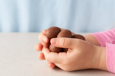 Child's hands holding chocolate Easter eggs with coopy space. Side viewの写真素材