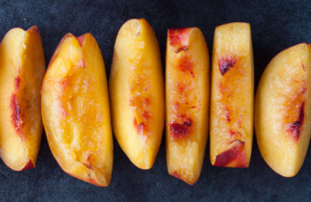 Extreme closeup of yellow nectarine peach slices on dark background. Top view.の写真素材