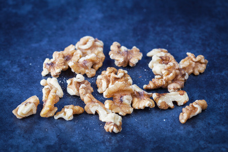 Scattered shelled walnuts on grunge textured surface. Shallow depth of field
