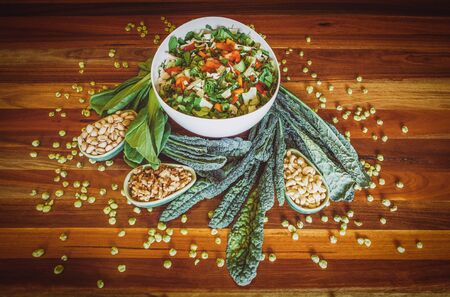 Fresh healthy salad in white bowl with kale leafs and nuts on wooden table. Healthy food concept. Image has vintage filter applied.の写真素材