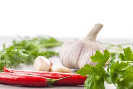 Garlic, red hot chilli peppers, and parsley on bright background. Shallow depth of field.の写真素材