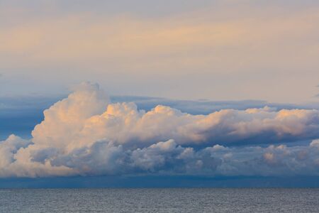 Low dramatic fluffy clouds over sea water