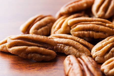 Pecans on wooden table extreme closeup with copy space. Shallow depth of field.