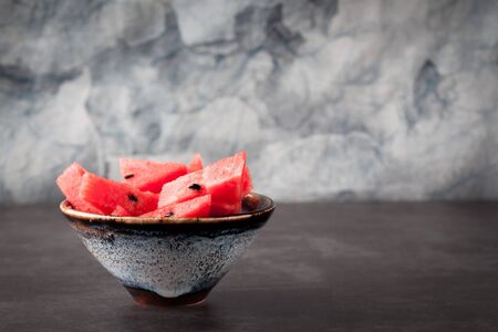 Sliced watermelon in handmade ceramic bowl on blurred  background with copy space. Shallow depth of field.の写真素材