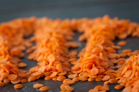Red lentils on dark surface closeup. Shallow depth of field.の写真素材