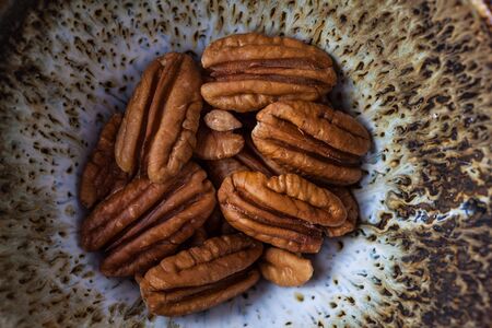 Pecans in handmade ceramic bowl extreme closeup, top view.の写真素材