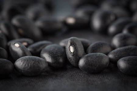 Black turtle beans on dark surface extreme closeup. Shallow depth of field.の写真素材