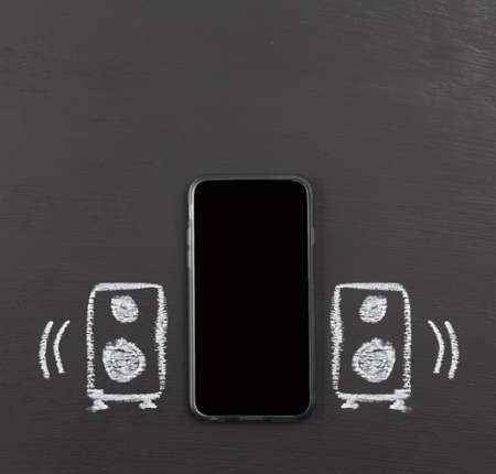 Front facing speakers on mobile phone concept hand drawn with chalk on blackboard with copy space.の写真素材