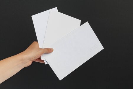 Female hand delivering three postage envelopes on black backgroundの写真素材