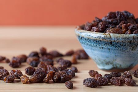 Organic raisins in handmade ceramic bowl on wooden table. Horizontal image with copy space. Shallow depth of field.の写真素材