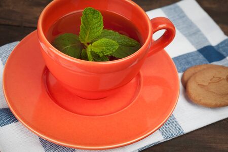 Closeup of range teacup with tea and mint placed on teatowel together with cookies. Shallow depth of field.の写真素材