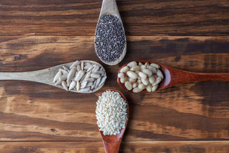 Sunflower, black Chia, sesame seeds and pine nuts in wooden spoons. Top view with copy space.の写真素材