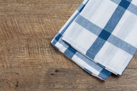 Checkered white blue kitchen towel on walnut wood background. Horizontal image, top view with copy space.の写真素材