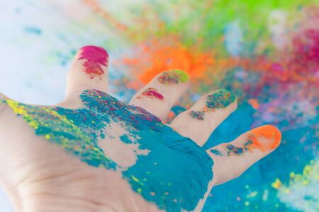 Open hand painted with Holi powder with blurred colorful backgroundの写真素材