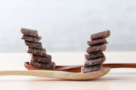 Cooking chocolate chunks balanced on top of each other on wooden spoons with copy spaceの写真素材