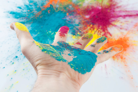 Open hand painted with Holi powder with blurred colorful backgroundの写真素材